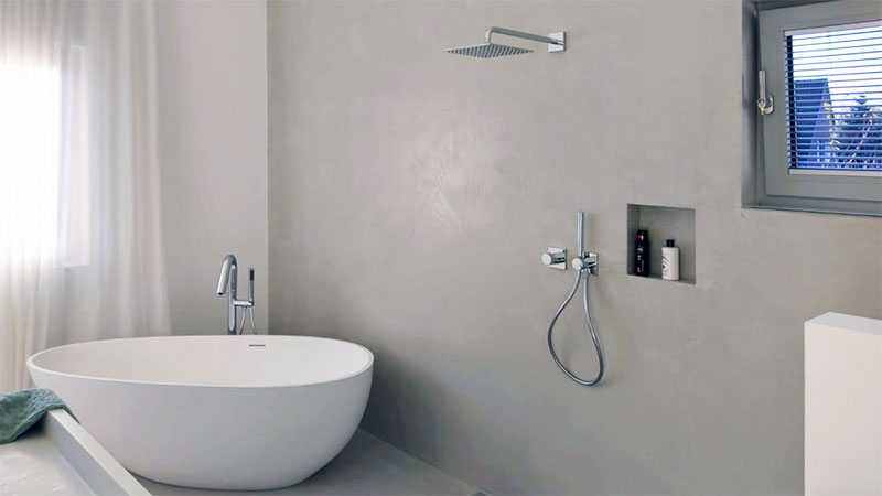 A modern bathroom with freestanding tub and resin walling